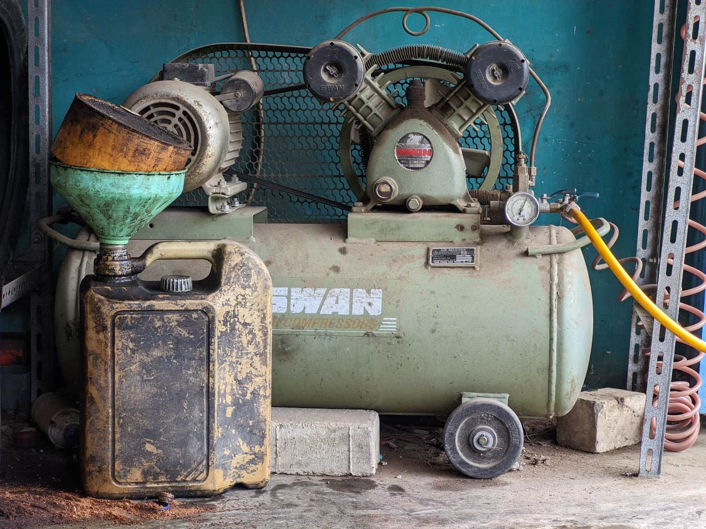 An air compressor in a home garage workshop with tools nearby