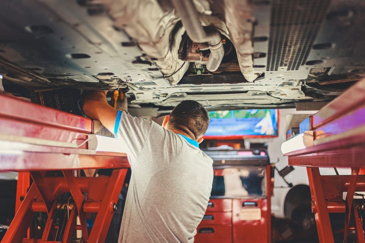 A mechanic working underneath a car with tools laid out