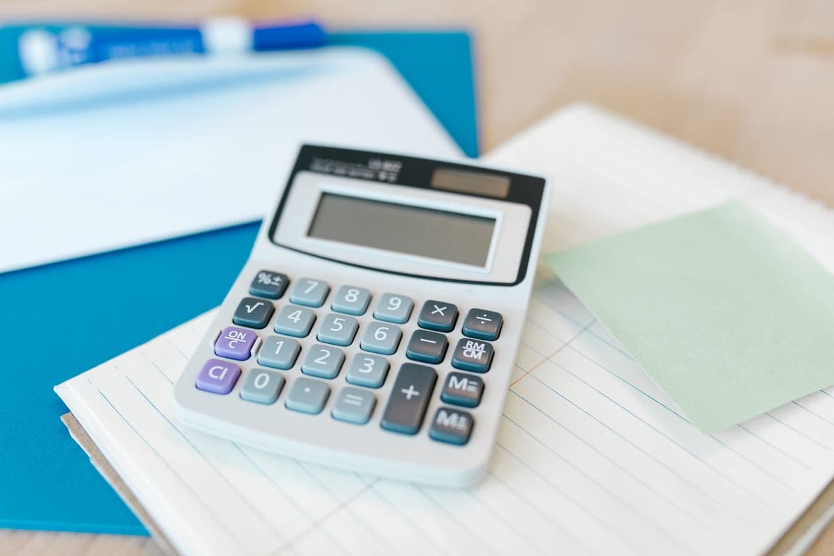 A calculator and notepad on a desk next to technical notes